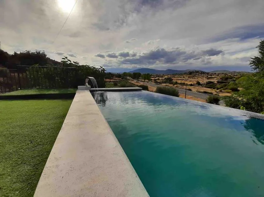 Piscina alargada de agua verde con hierba y montañas al fondo