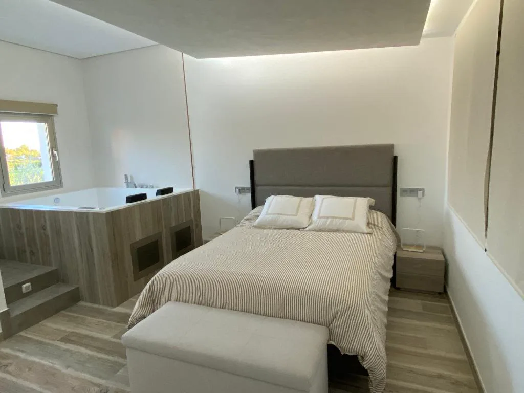 Habitación con cama grande y jacuzzi al fondo
