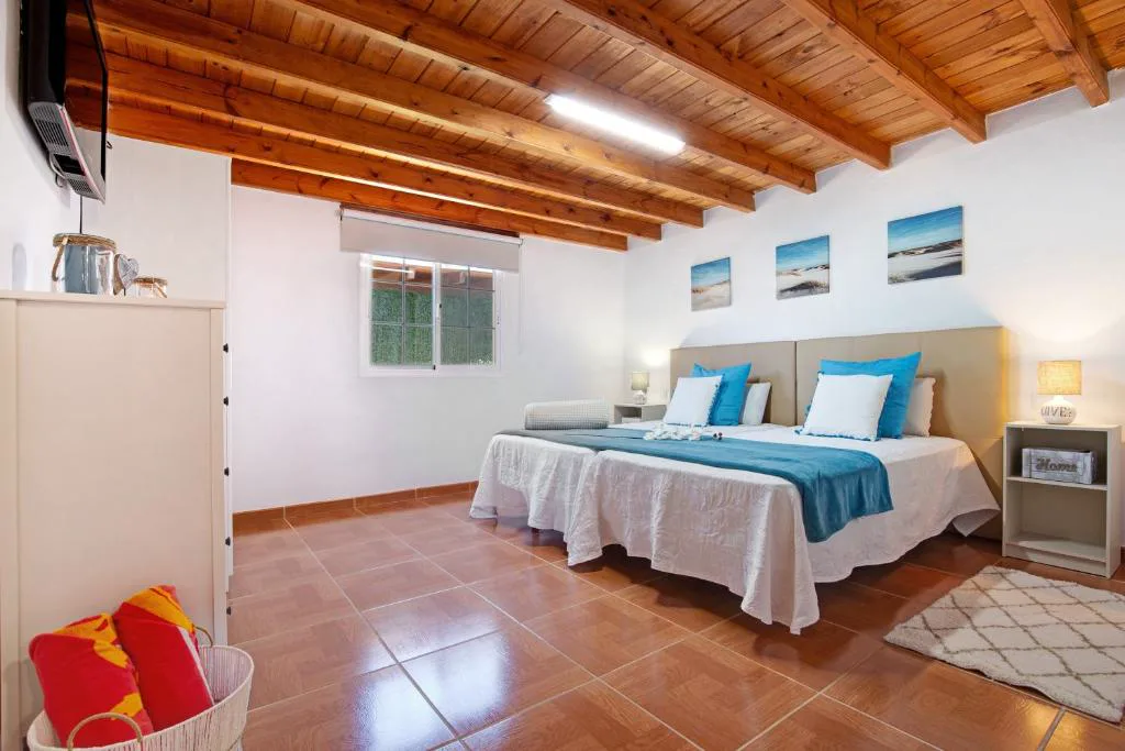 Dormitorio con techo de madera de vigas y ropa de cama azul turquesa, Casa Valentina
