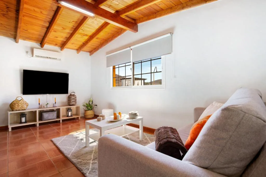 Salón con sofás grises y techo de vigas de madera, Casa Valentina