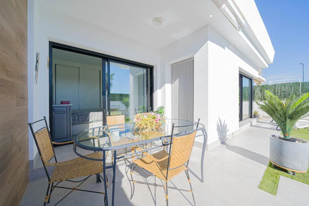 Terraza con mesa de cristal y sillas de mimbre