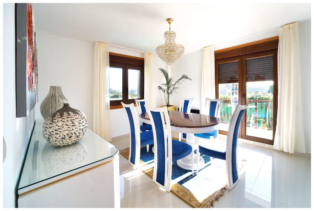 Comedor con mesa y sillas azules bajo lámpara de araña, Casa Victoria
