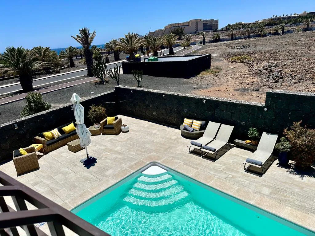 Vista aérea de la piscina junto al paisaje volcánico negro de Lanzarote, Casa Volcanes