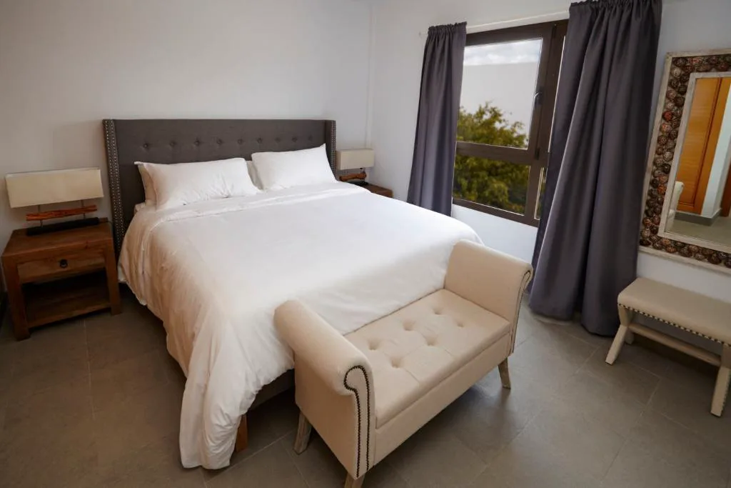 Dormitorio con cabecero gris y espejo artesanal de mosaico, Casa Volcanes