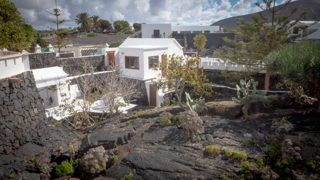 Casa blanca tradicional construida sobre roca volcánica negra entre cactus, Casa volcánica El Cabezo, en Masdache, Lanzarote