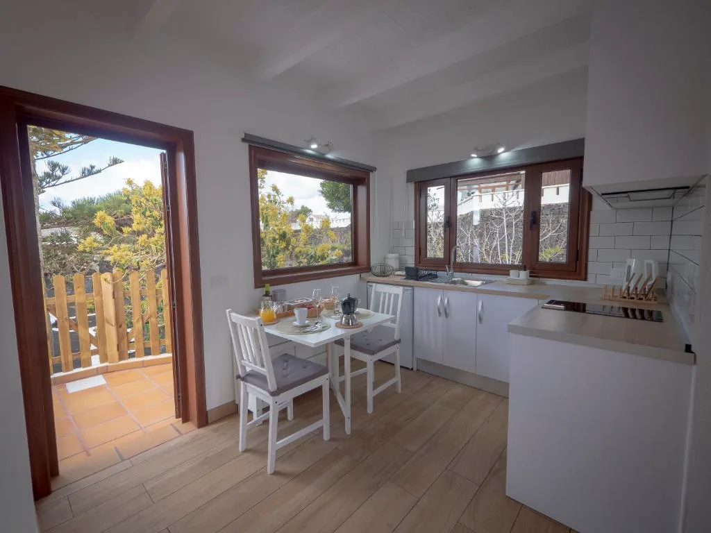 Cocina con mesa de desayuno junto a puerta abierta al jardín volcánico, Casa volcánica El Cabezo