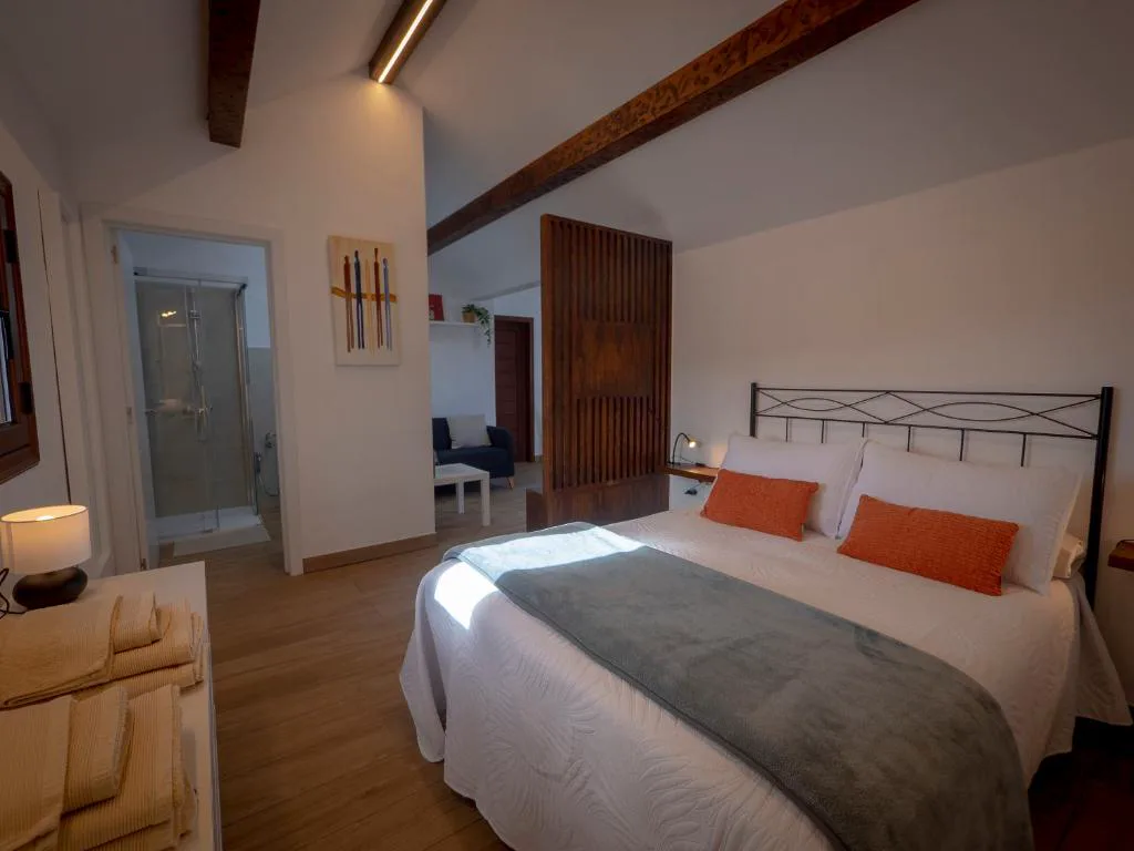 Dormitorio con techo de vigas de madera y separador de listones tallados, Casa volcánica El Cabezo