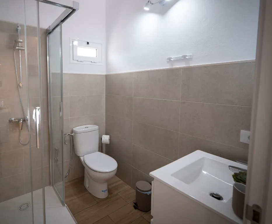 Baño moderno con ducha de mampara de vidrio y azulejos beige, Casa volcánica El Cabezo