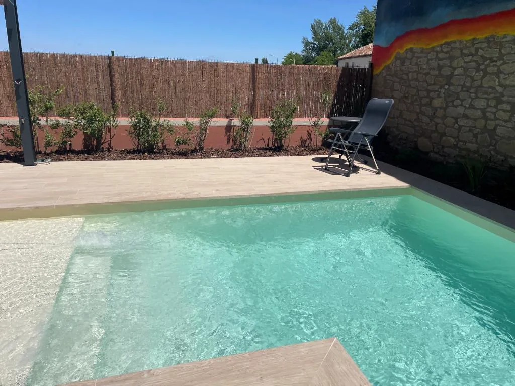 Piscina pequeña de agua turquesa junto a una pared de ladrillo