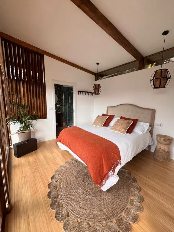 Dormitorio con cama doble y ropa de cama en tonos tierra, en una cabaña de Casal Oseira