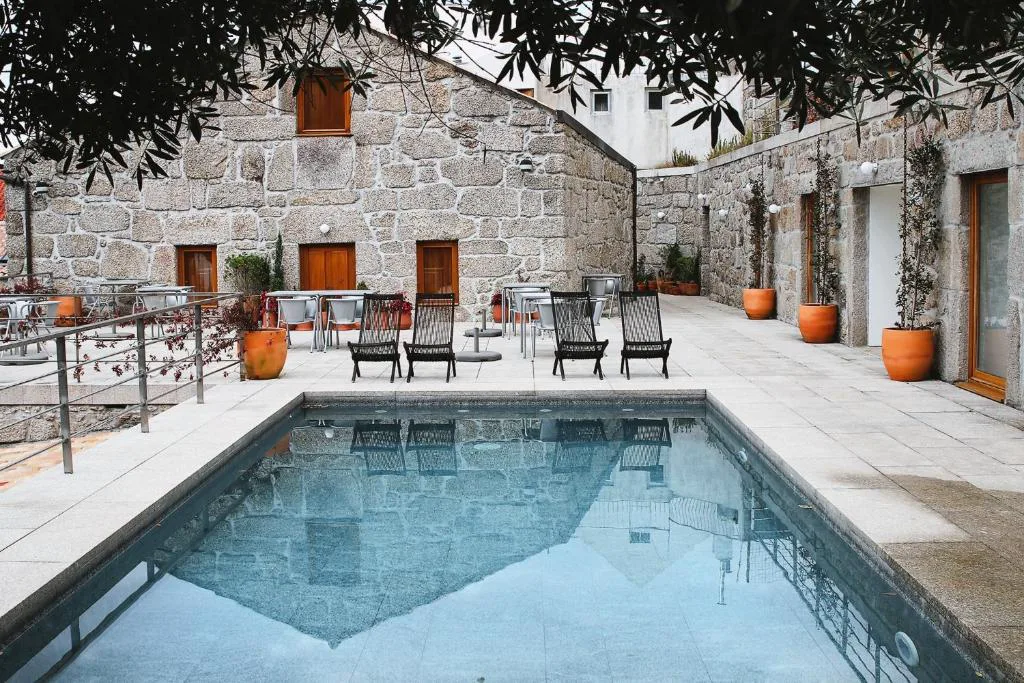 Piscina en el patio de piedra granítica de Casas da Lapa, junto al edificio principal