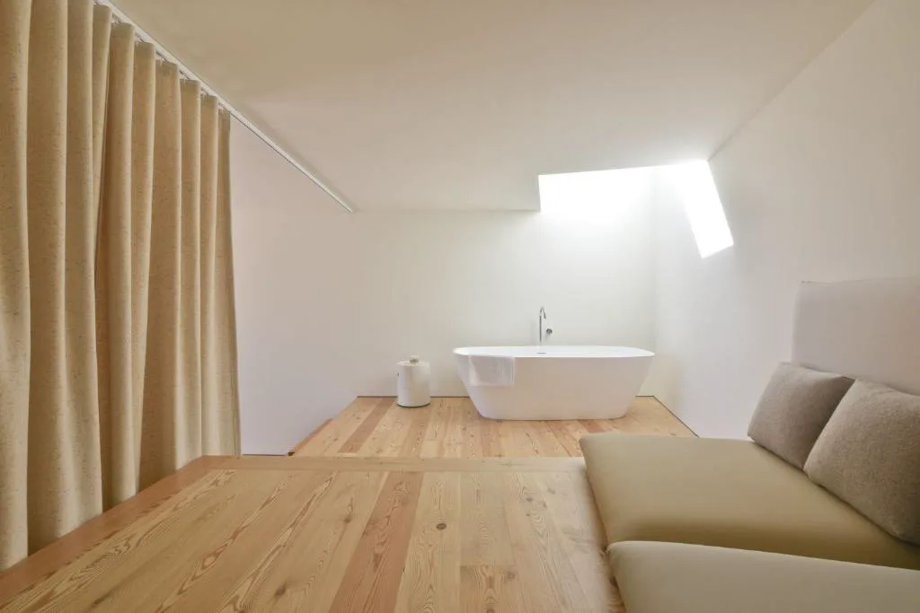Baño con bañera exenta bajo un lucernario de luz natural, Casas da Lapa