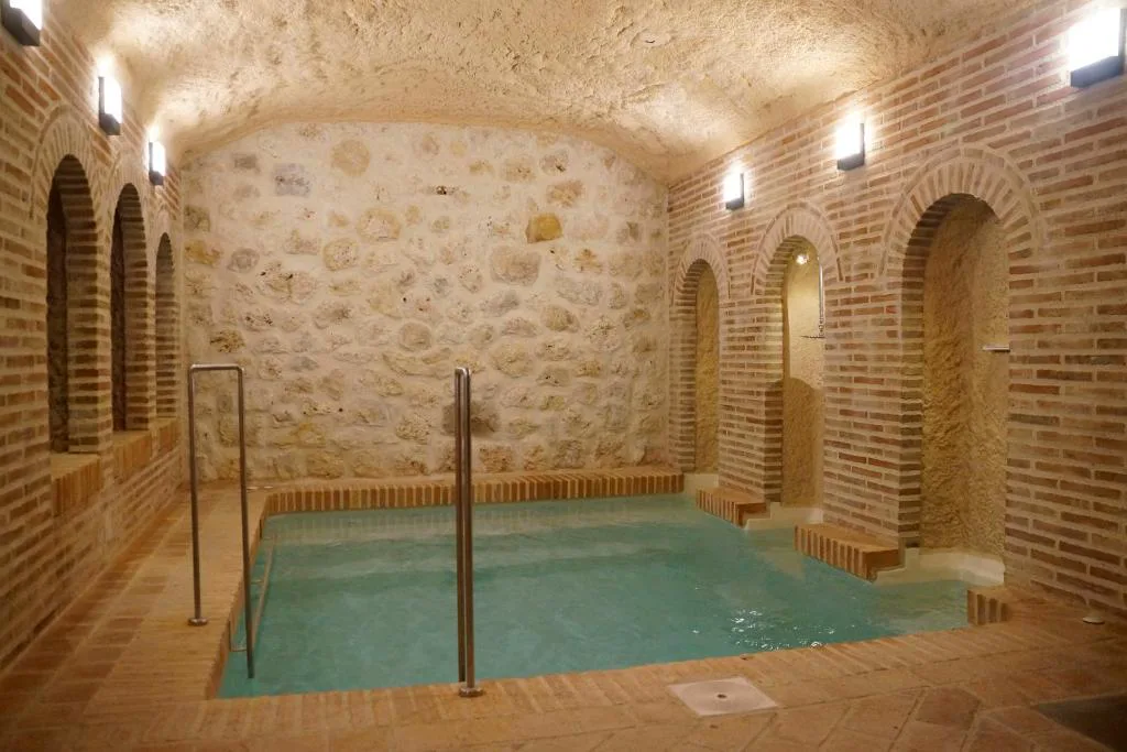 Sala de spa de piedra con arcos y piscina de hidromasaje
