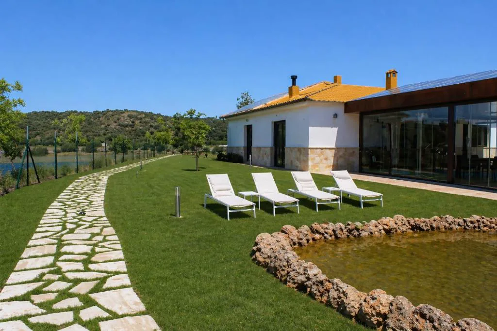 Casa blanca con tumbonas y camino de piedra sobre el césped