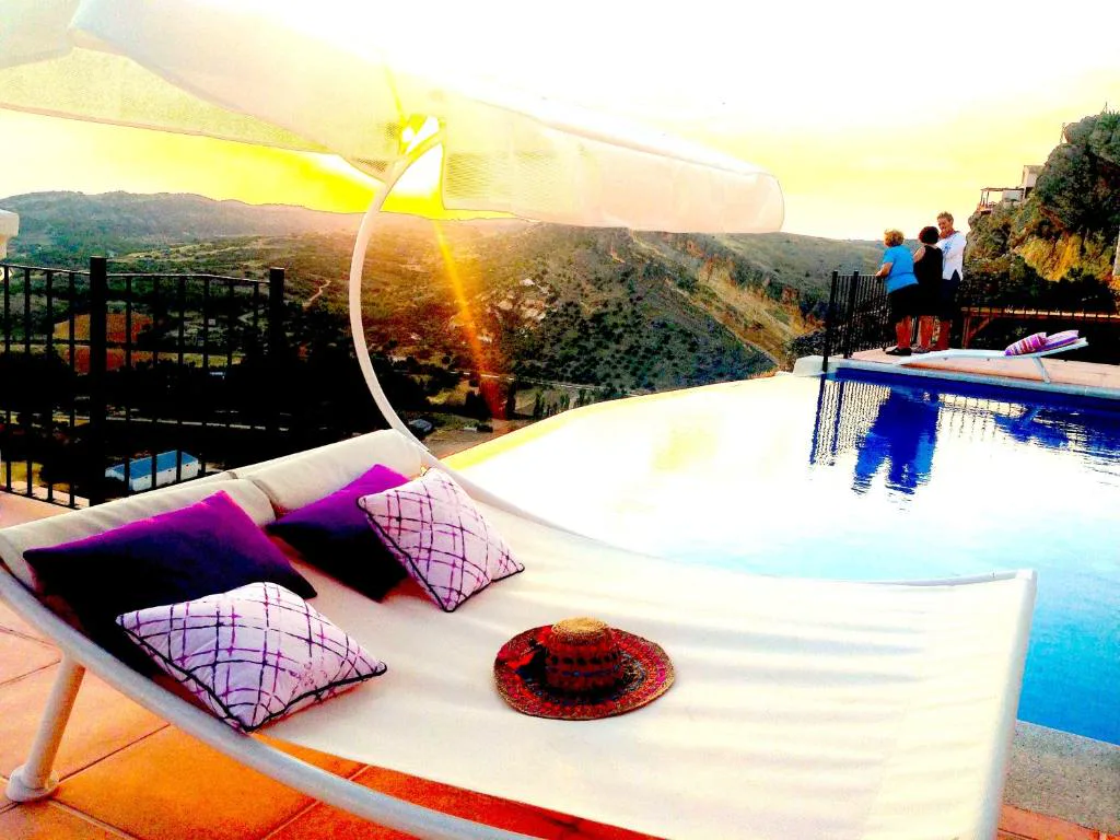 Piscina infinita con vistas al atardecer y almohadones violeta