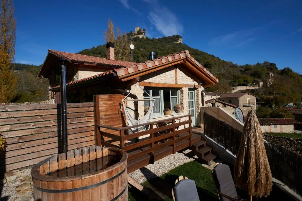 Casa de madera y piedra con jacuzzi de madera en la terraza