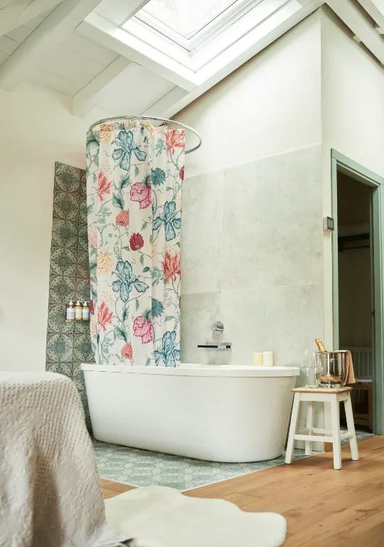 Baño con bañera exenta y cortina floral