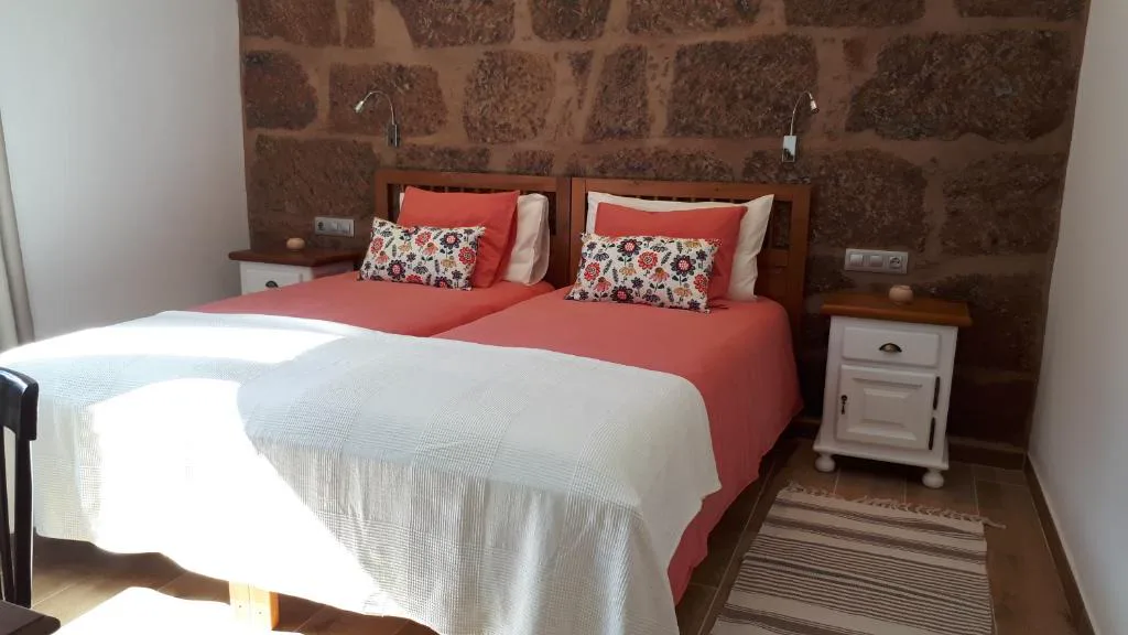 Dormitorio con pared de piedra vista y cabeceros de madera, Casita Tio Manuel