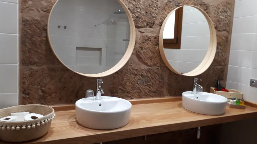 Baño con dos espejos circulares de madera y lavabos de sobre bol, Casita Tio Manuel