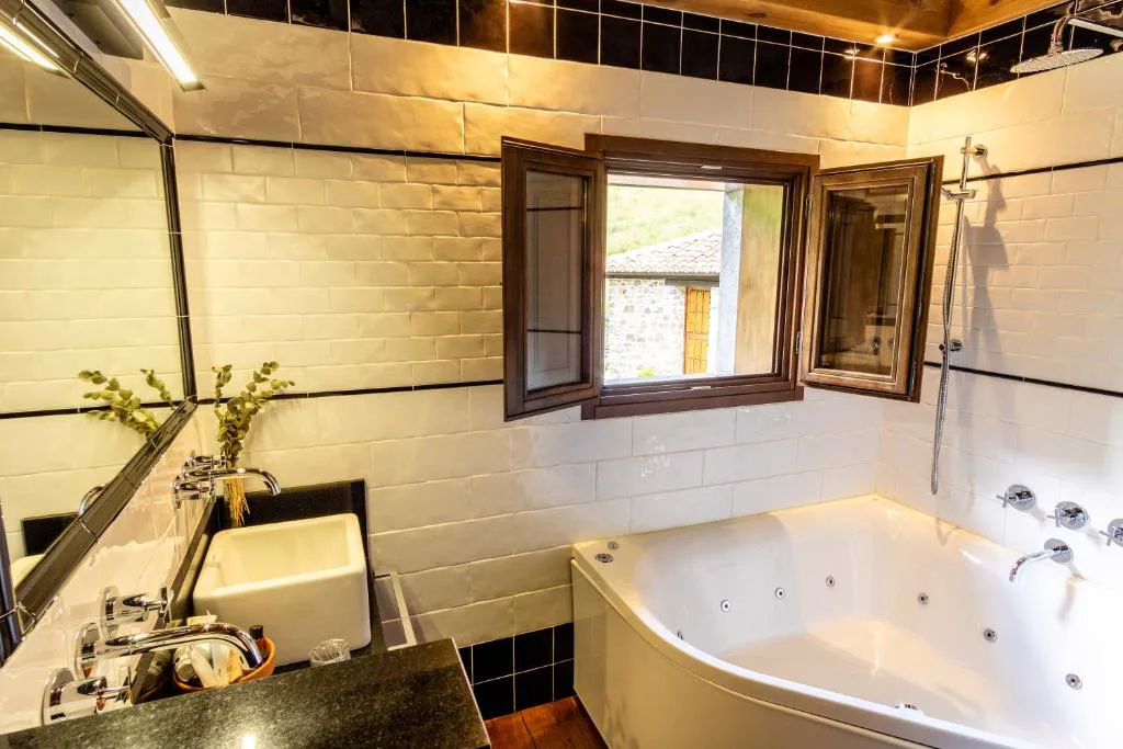 Baño con bañera de hidromasaje de esquina y ventana de madera
