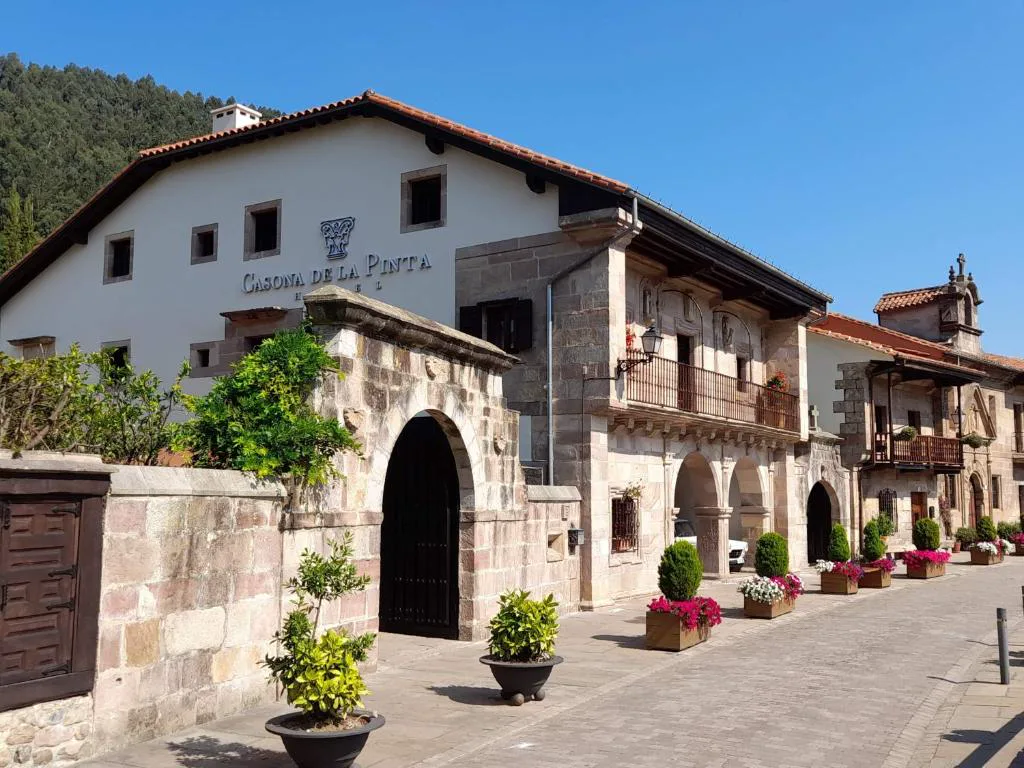 Fachada de piedra y blanco con arco y plantas