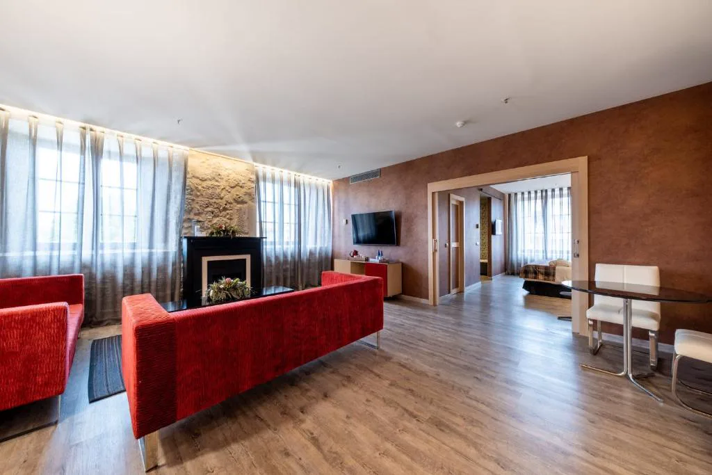 Suite con salón de sofás rojos y chimenea decorativa