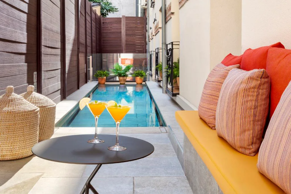 Piscina estrecha con cojines naranjas y dos copas