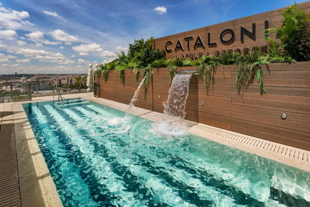 Piscina alargada de mosaico azul con cascada en una azotea