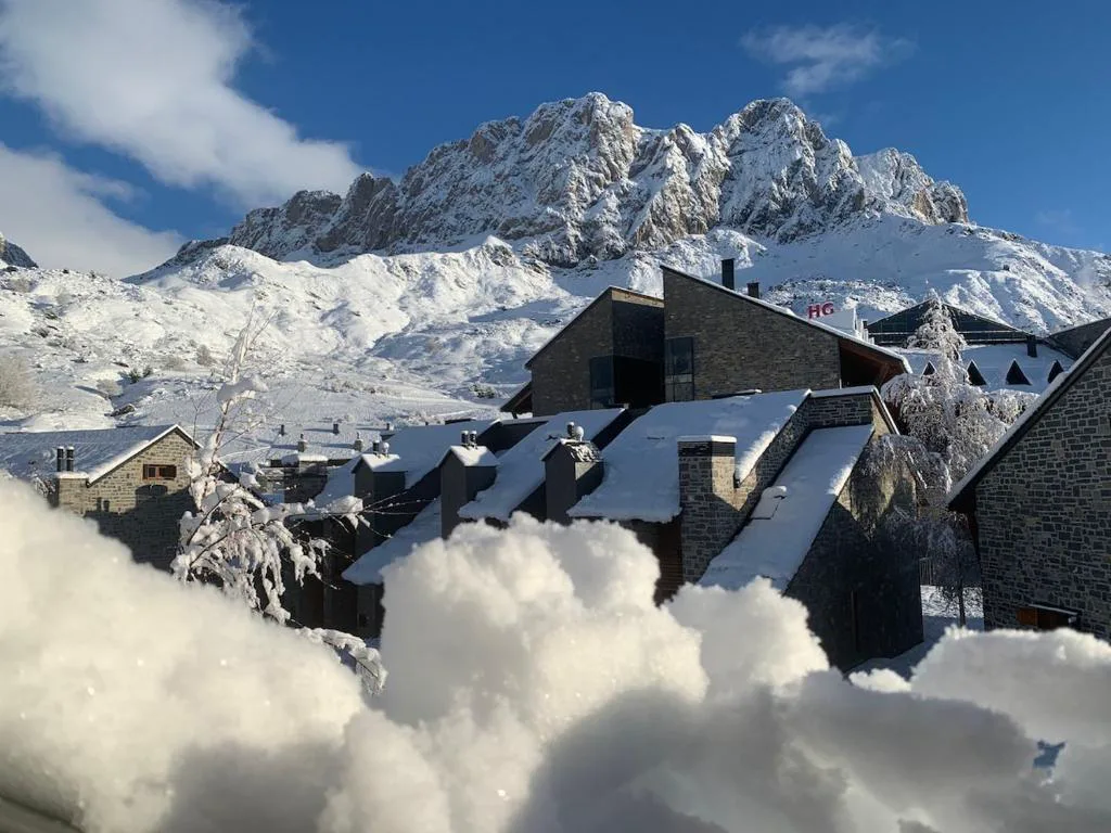 Chalets de montaña con nieve y picos al fondo