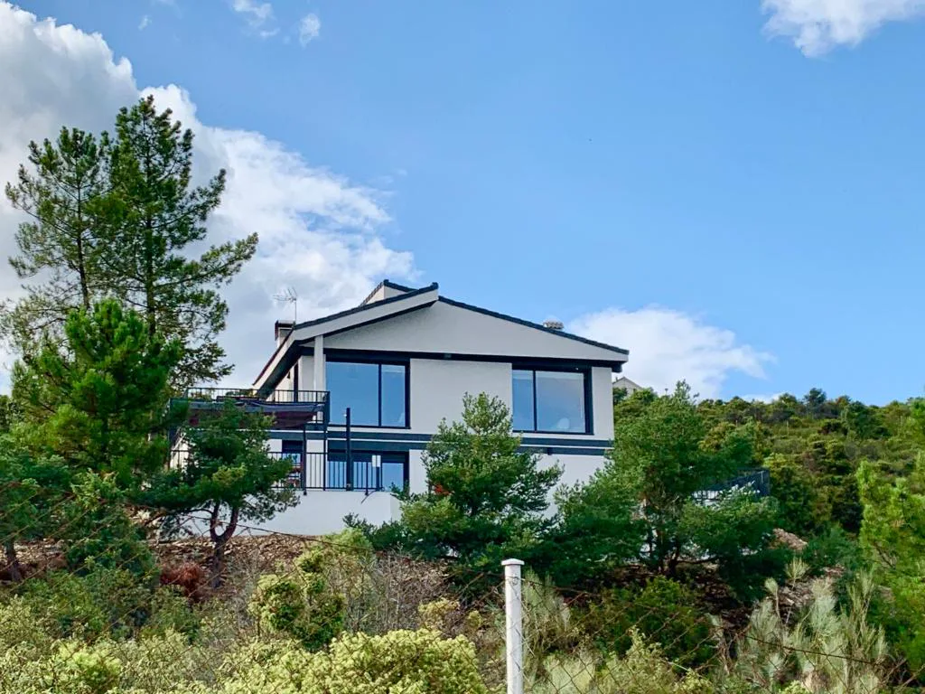Casa moderna de dos alturas entre pinos con terraza y fachada blanca