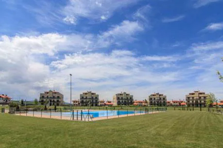 Piscina comunitaria con césped y adosados al fondo