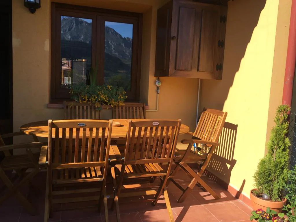 Terraza cubierta con mesa de madera y sillas plegables