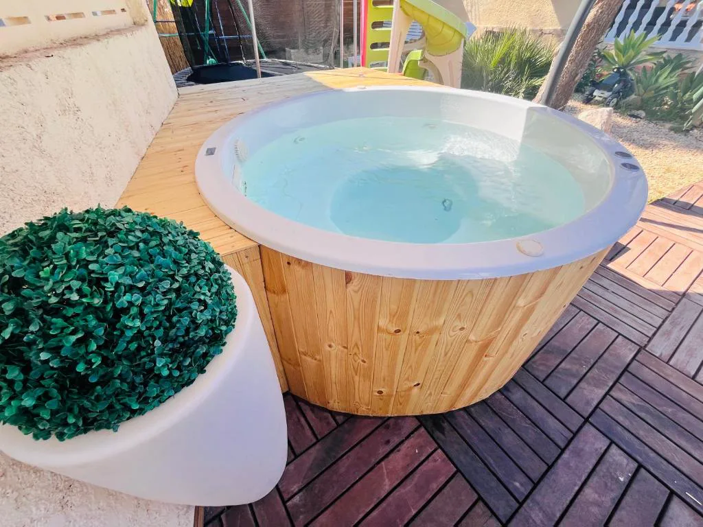 Jacuzzi de madera con agua y vegetación alrededor