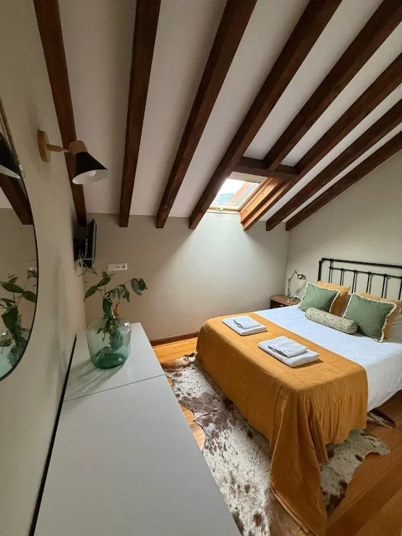 Dormitorio con vigas de madera y colcha mostaza