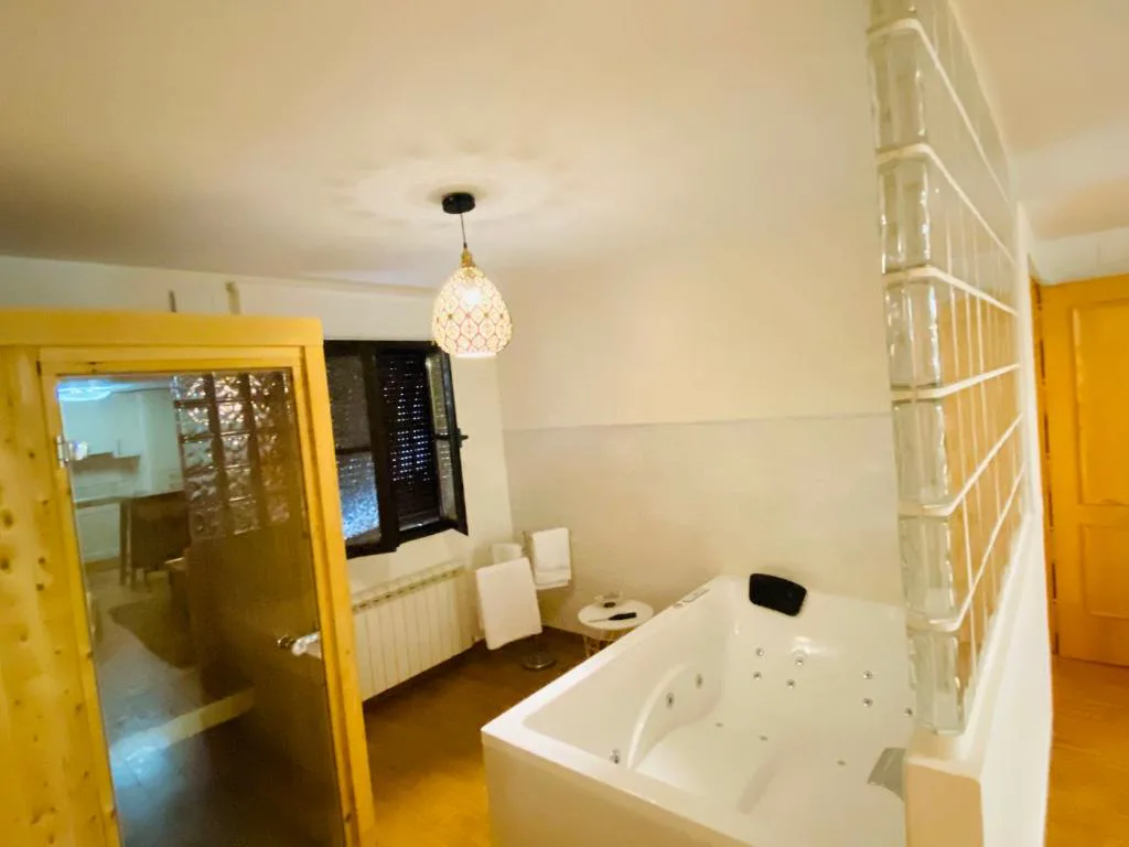 Bañera de hidromasaje con puertas de madera junto a la cama