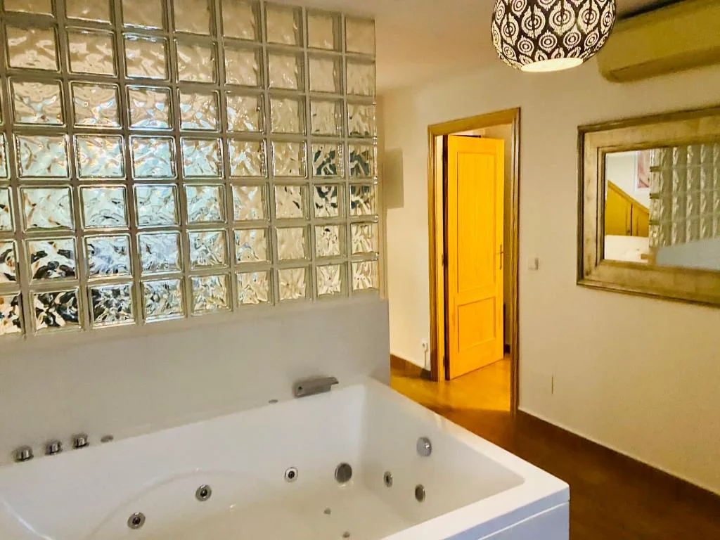 Bañera de hidromasaje con pared de bloques de cristal