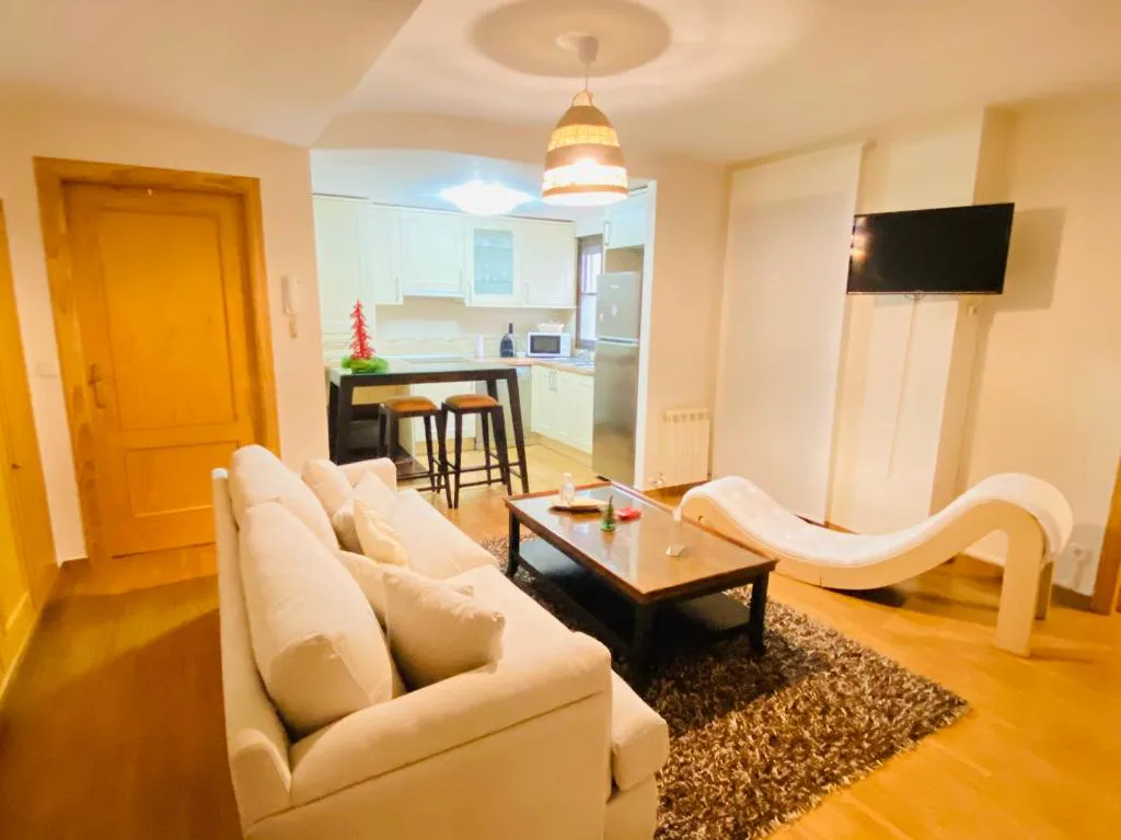 Salón con sofá y chaise longue blancas junto a la cocina