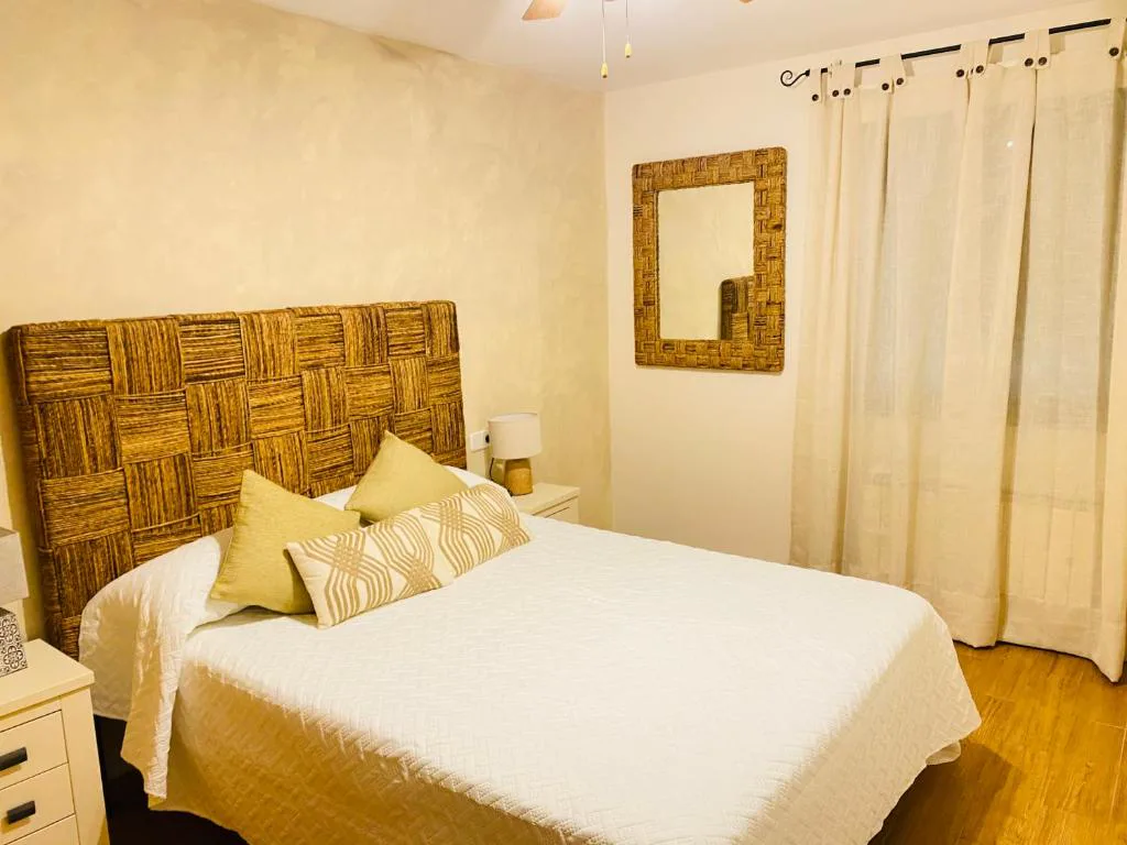 Dormitorio con cabecero de mimbre y mesillas