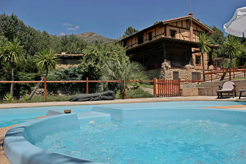 Piscina azul entre jardines y cabañas de madera en la Vera