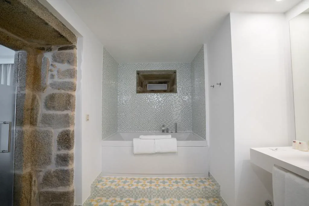 Baño con muro de piedra original y bañera de mosaico, Convento do Seixo