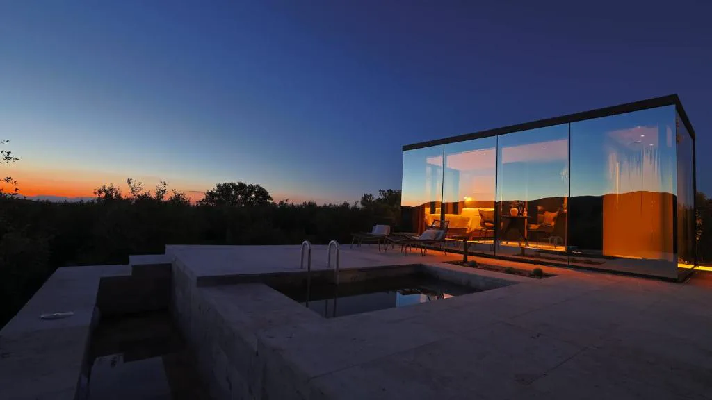 Cabaña de cristal al atardecer sobre el valle