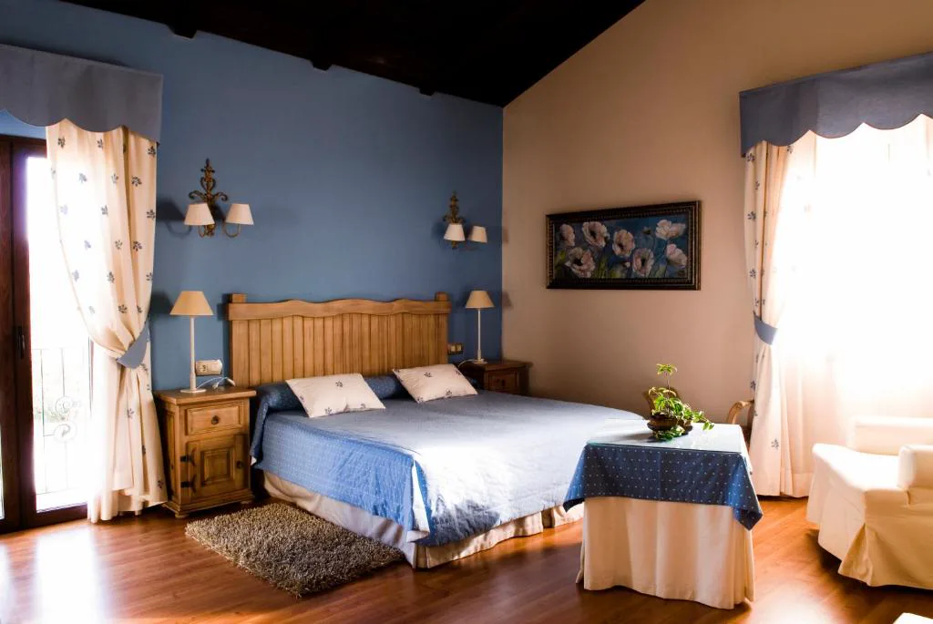 Habitación con paredes azules, cama doble y cortinas claras