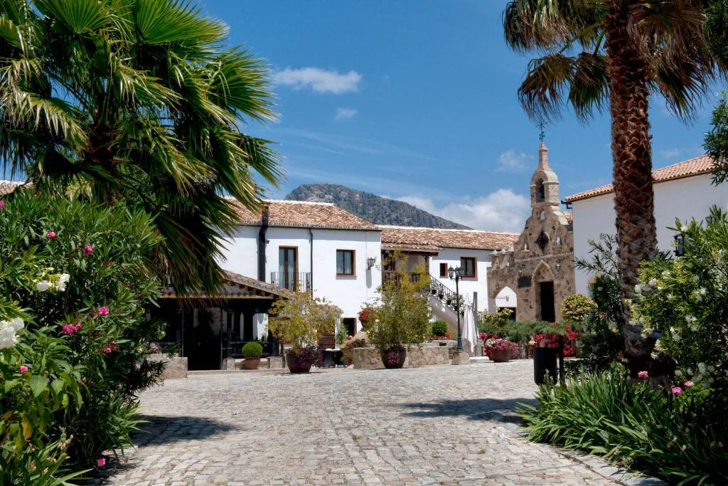 Plaza empedrada del cortijo con capilla y flores