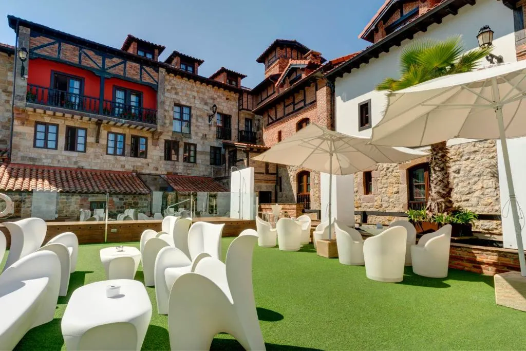 Terraza chill-out con césped artificial, sombrillas y mobiliario blanco de diseño en el patio del hotel