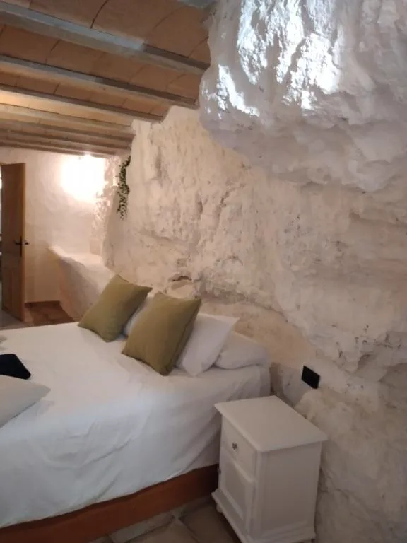 Habitación excavada en la roca con cama blanca