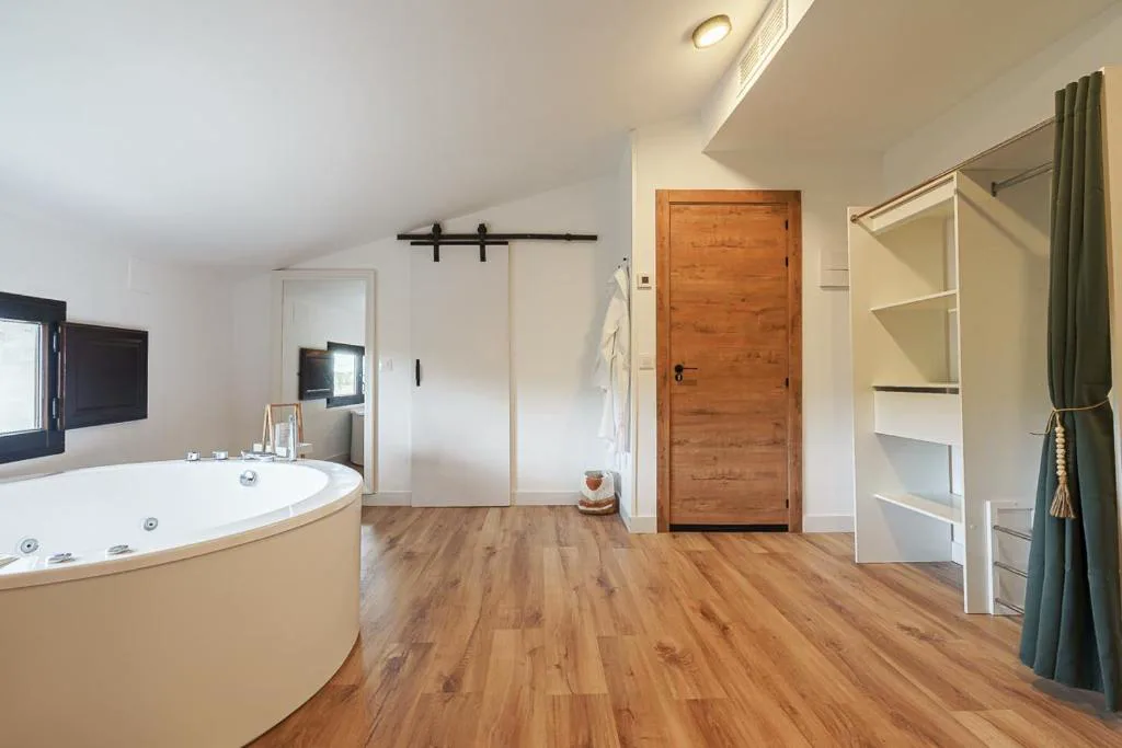 Jacuzzi blanco junto a una cama de la suite