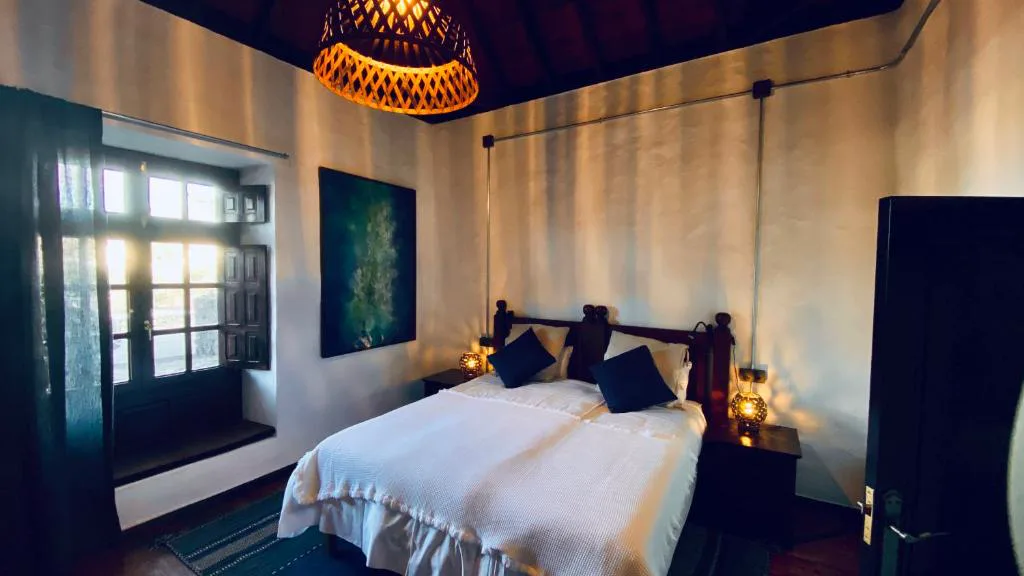 Dormitorio rústico con techo de madera y puerta abierta al patio, Eco-Finca Curbelo
