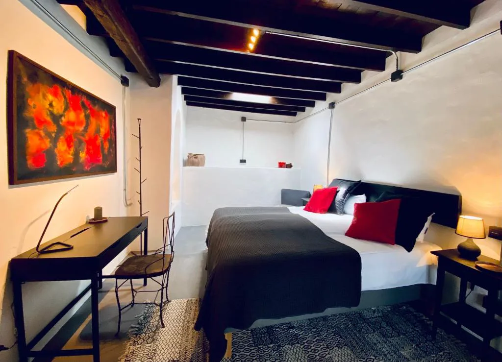 Dormitorio con vigas de madera vista y cuadro de colores cálidos, Eco-Finca Curbelo