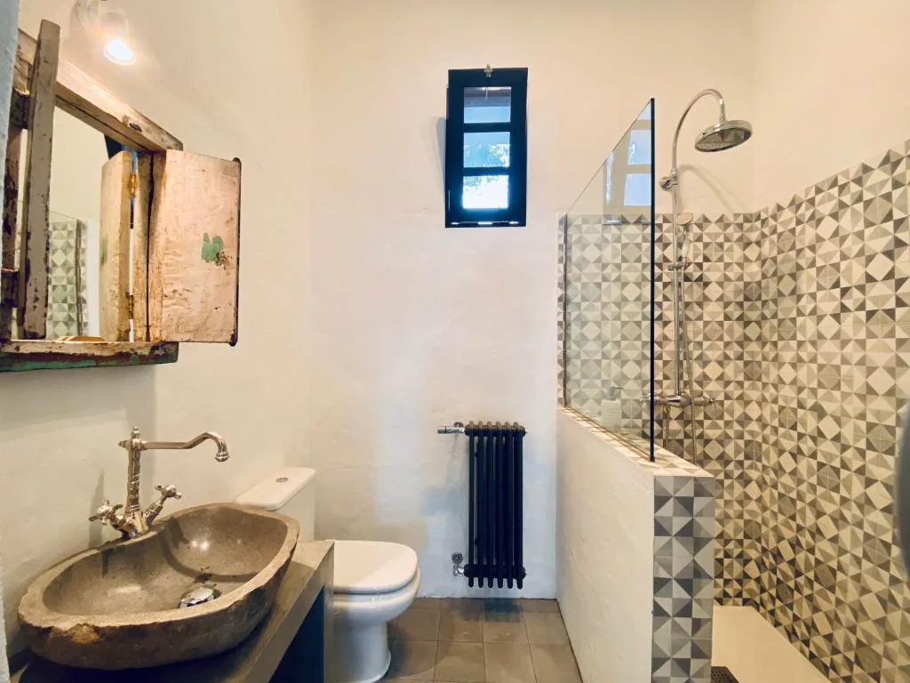 Baño rústico con lavabo de piedra volcánica y ducha de mosaico, Eco-Finca Curbelo