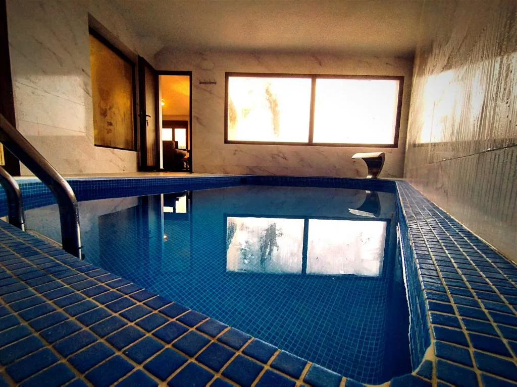 Piscina climatizada azul con ventanales y tumbonas